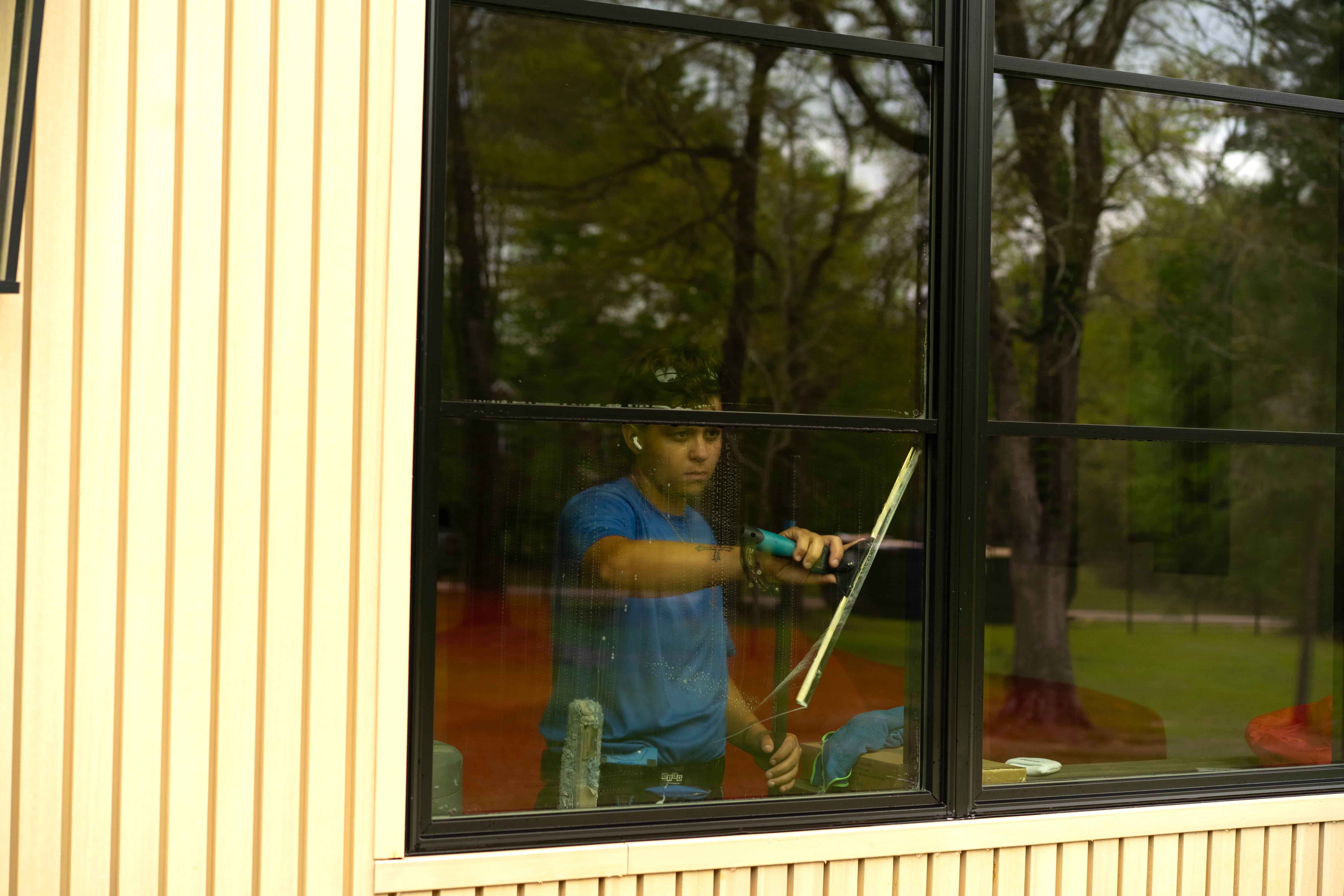 Window Warriors technician cleaning interior glass with a squeegee