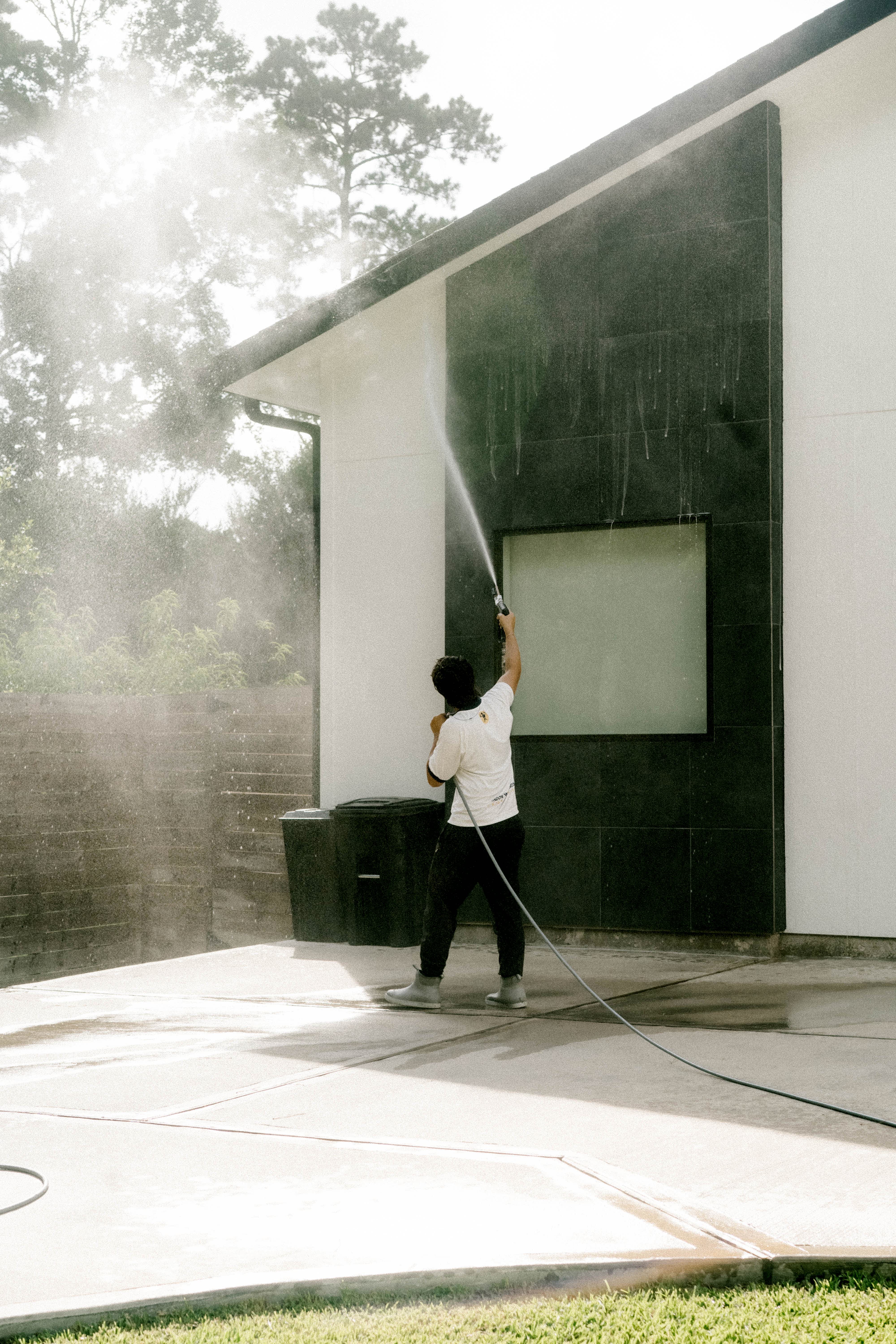 Pressure washing dark stone siding on a modern Houston home
